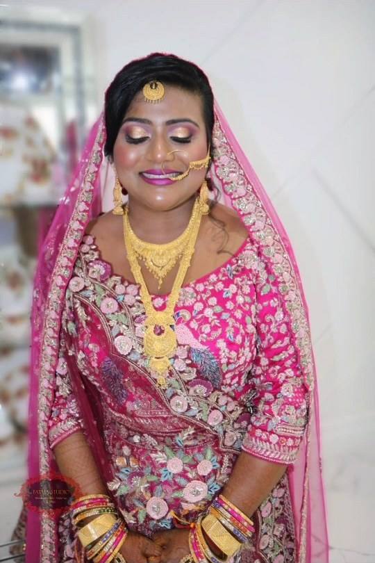 Bride in a pink dupatta with gold jewellery and soft pink bridal makeup