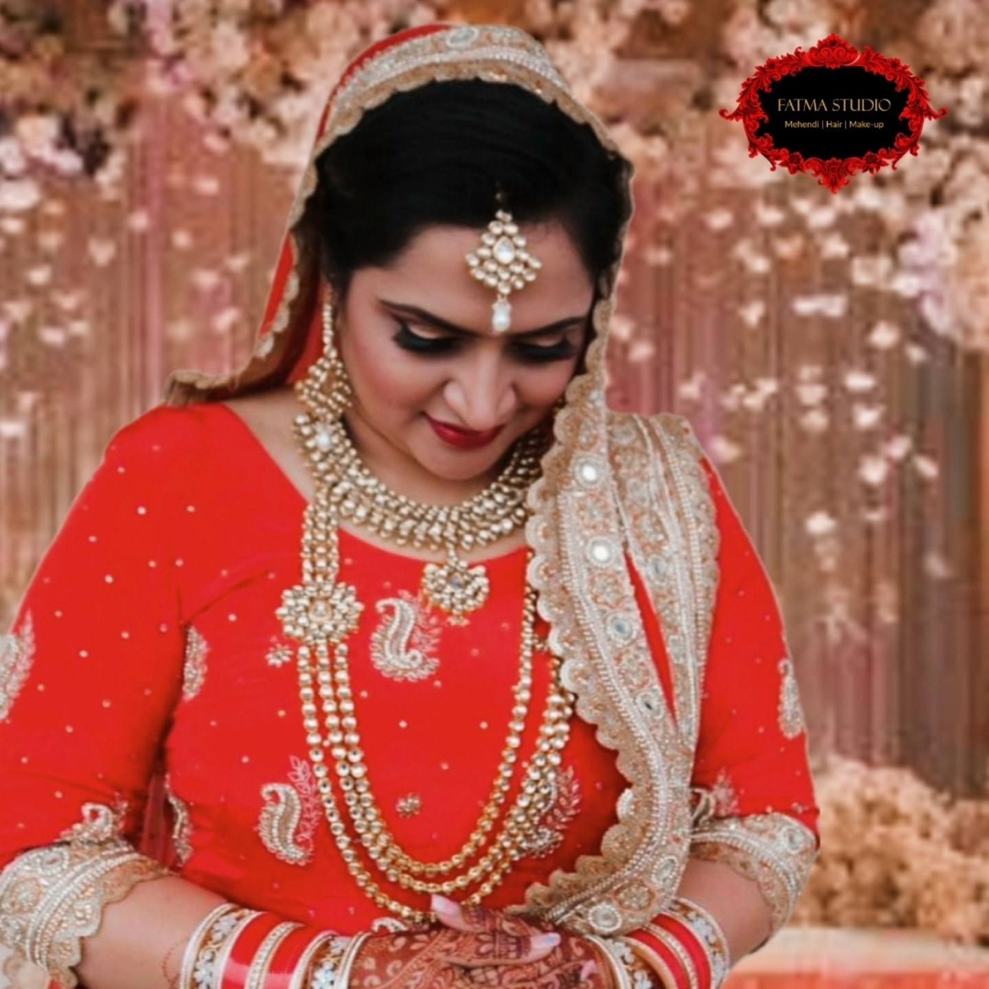 Bride in a red lehenga with layered gold jewellery and a bright, glowing bridal makeup look