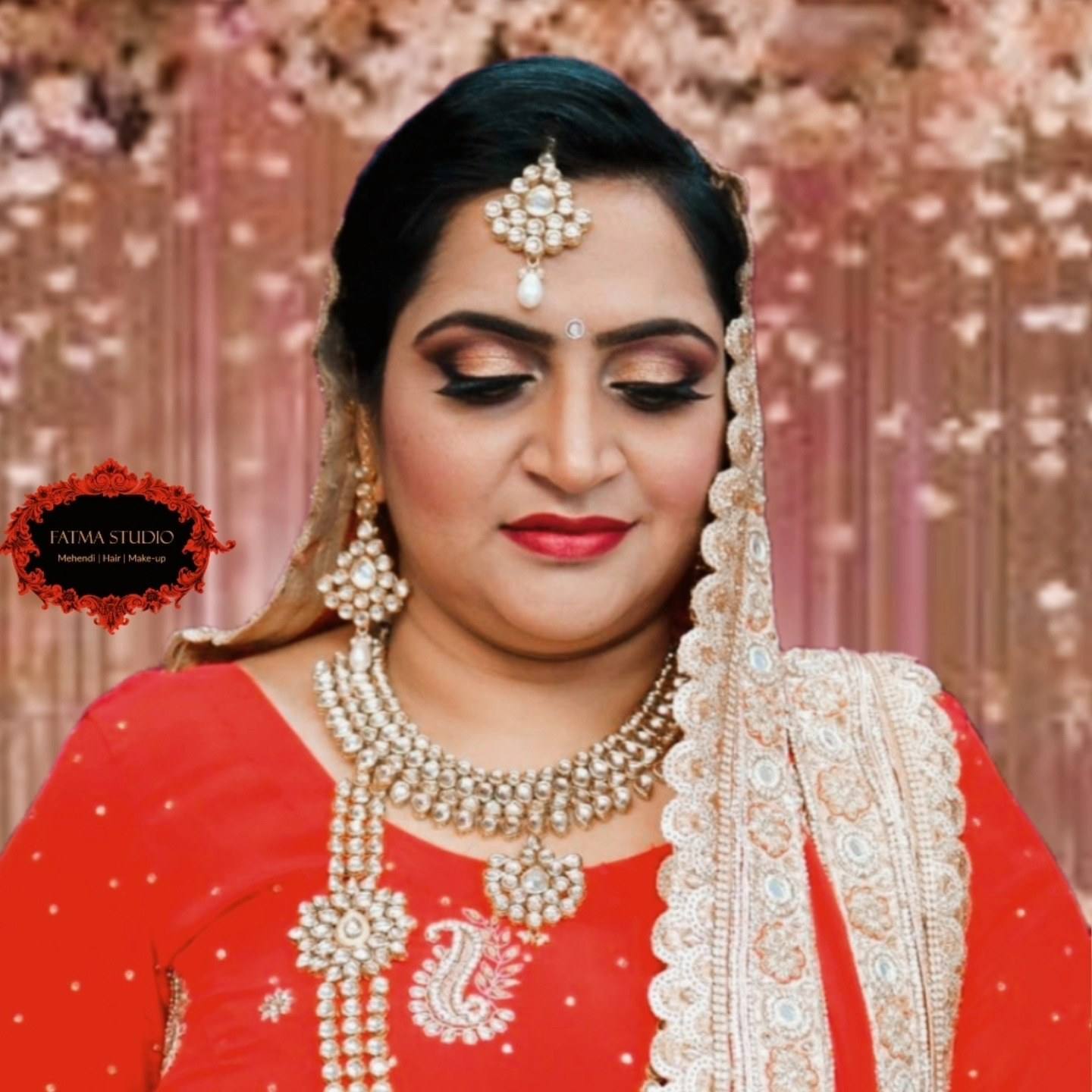 Close-up of a bride in red with gold jewellery, maang tikka and defined eye makeup