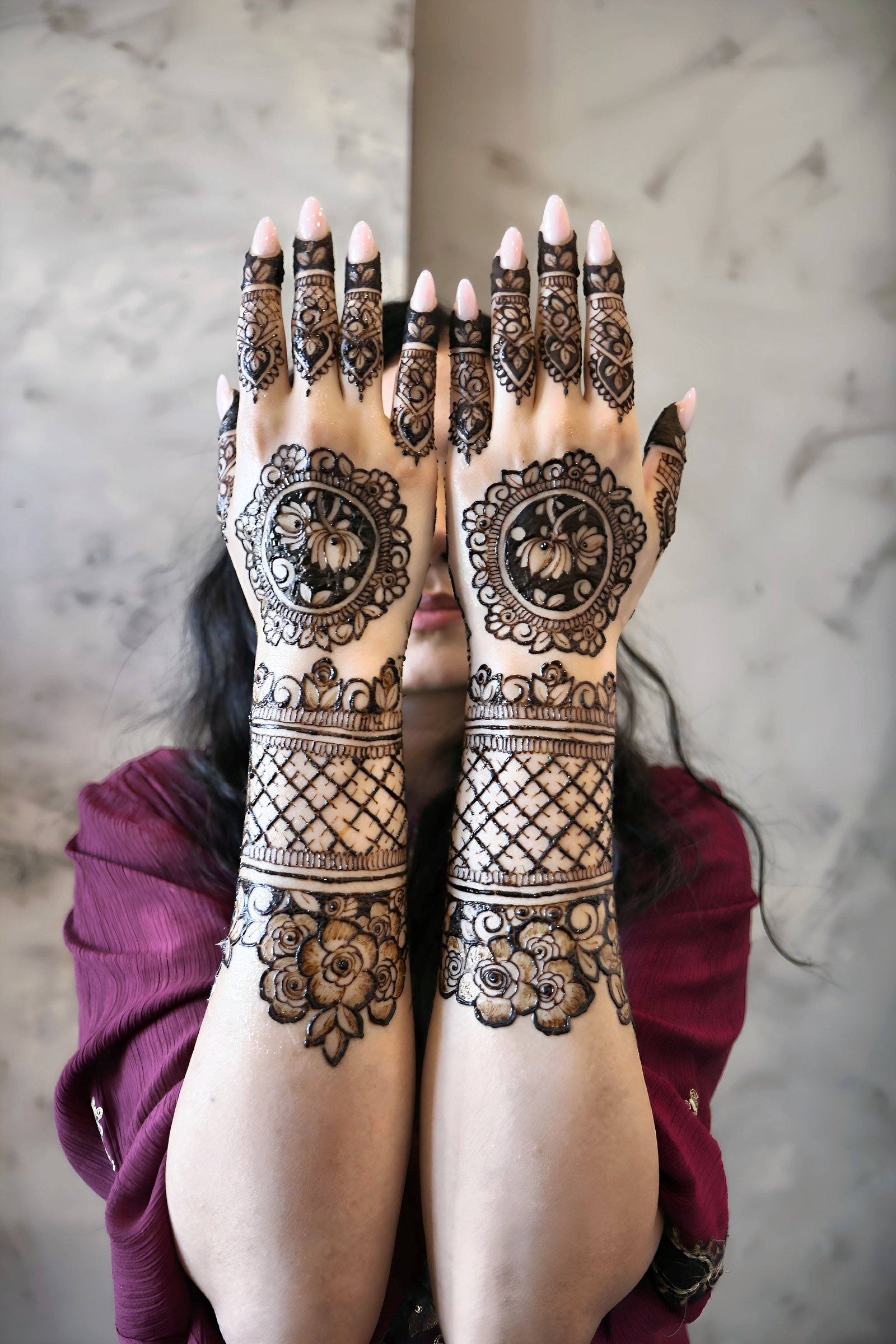 Bride covering her face with henna-adorned hands showing mandala designs