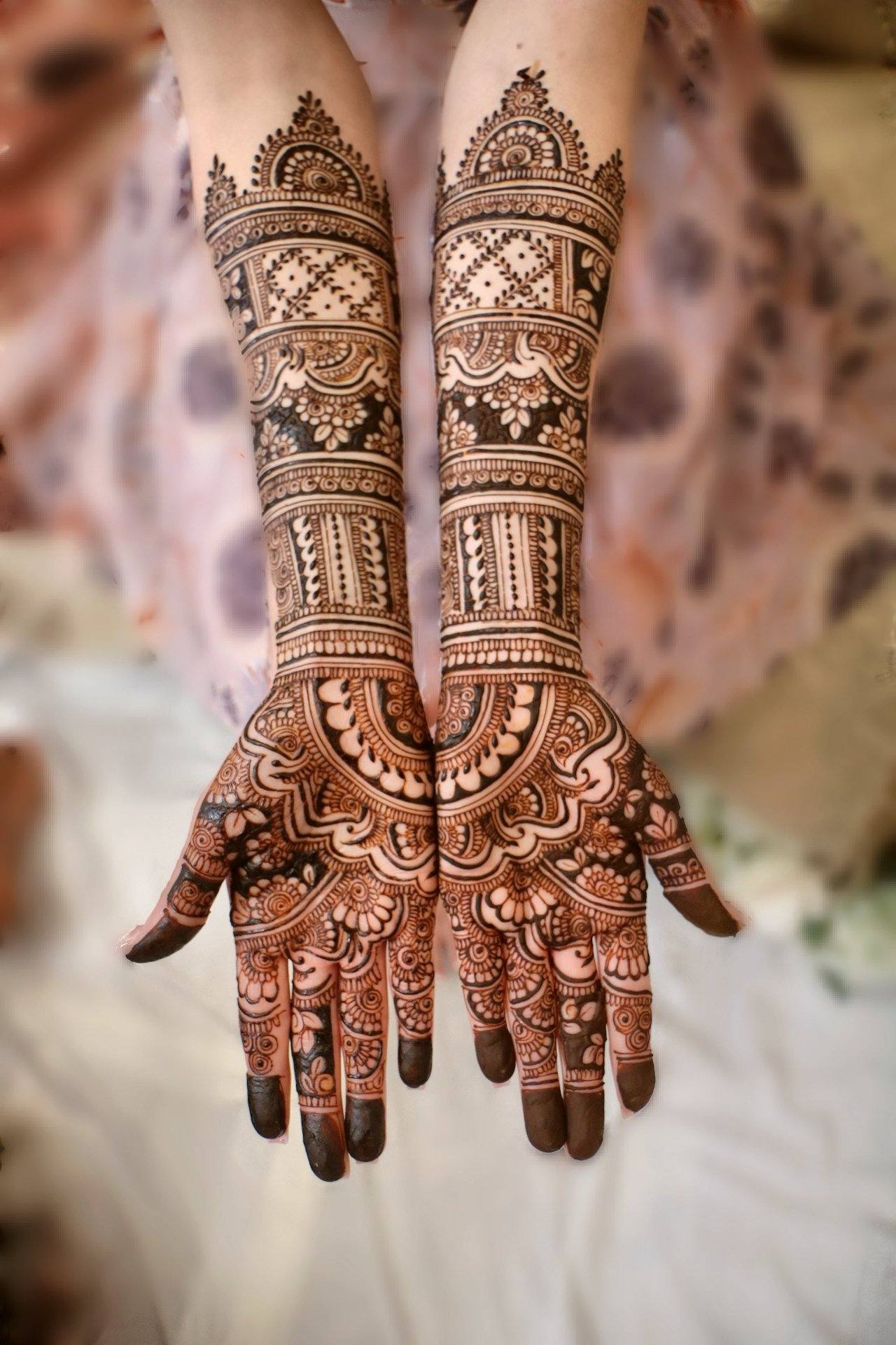 Bridal henna on both arms against a soft blurred background