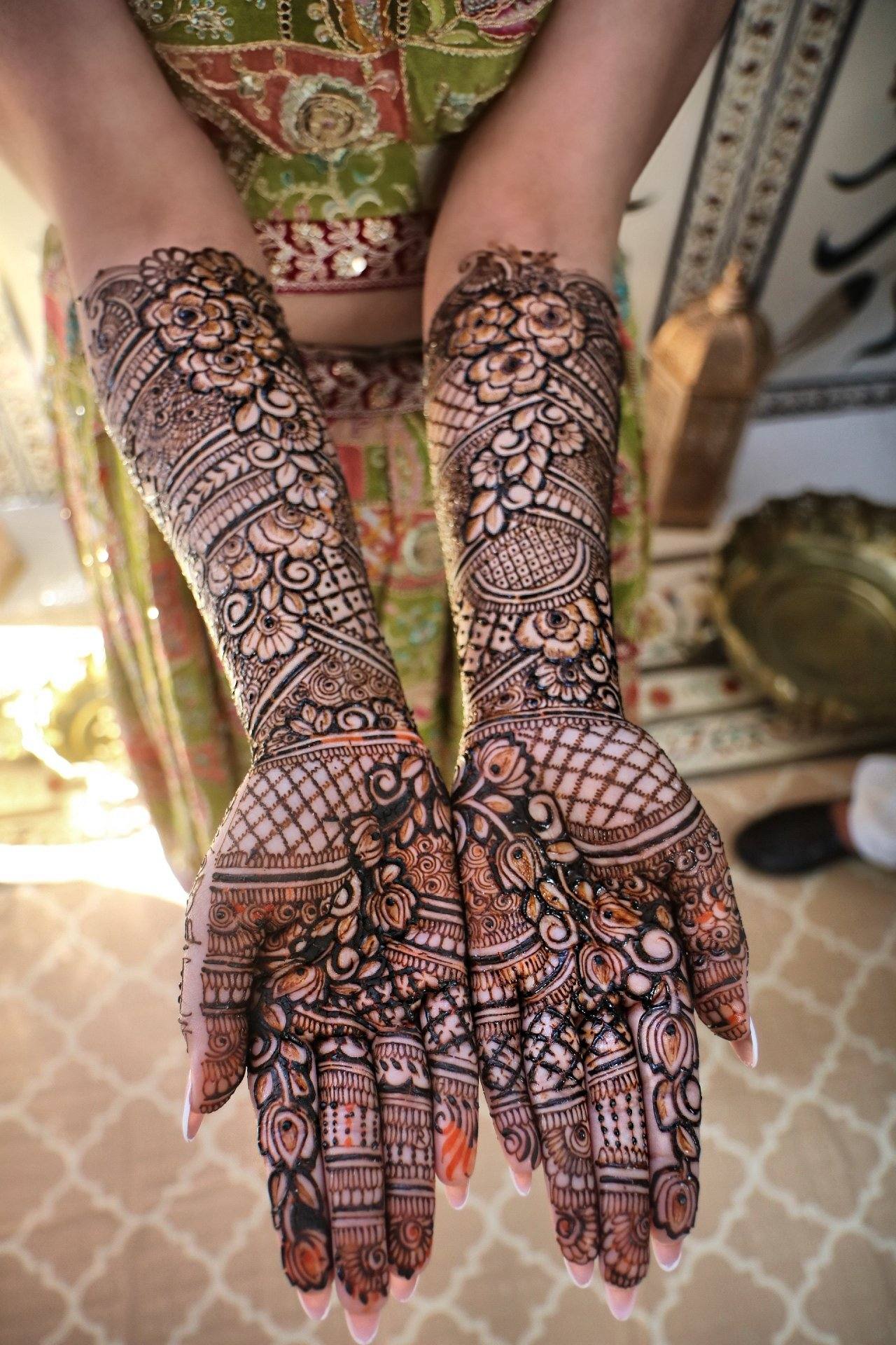 Dense floral bridal henna on palms and arms