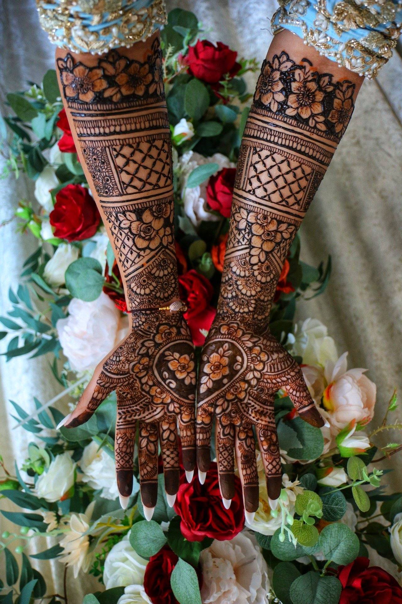 Bridal henna arms laid over red and white roses