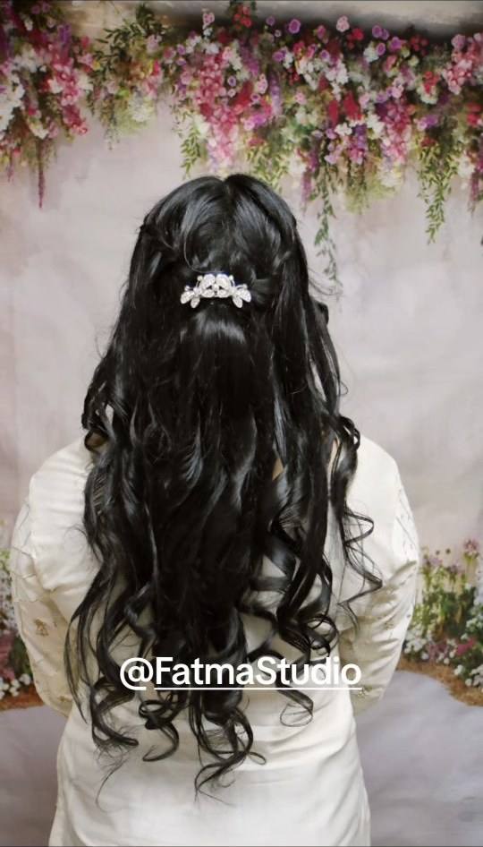 Long voluminous curls styled half-up with small pearl accents